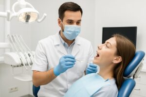 A modern dental office showcasing a dentist consulting with a patient about dental implant options, with digital X-rays displayed on a screen in the background. No text on the image.