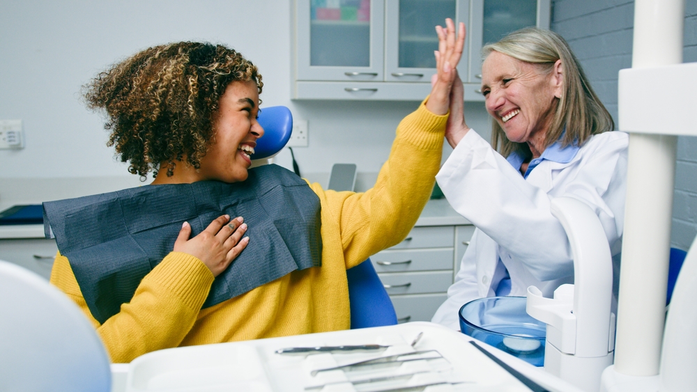 Image of a dental professional holding up various implant systems, including the implant fixture, abutments, connection screw, and prosthetic restoration. No text on the image.